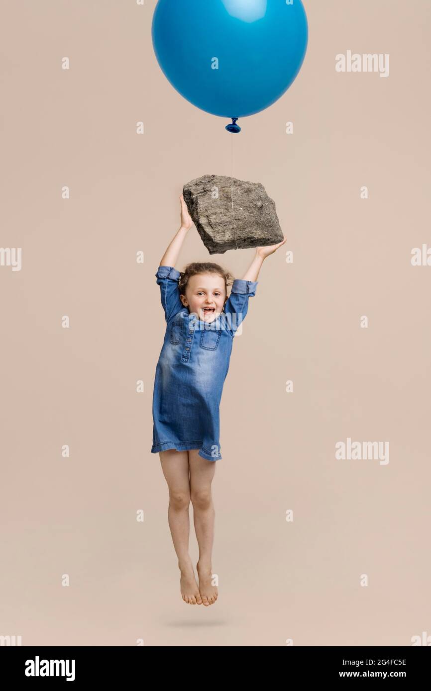 Mädchen hängt auf einem großen Stein mit Ballon Stockfoto