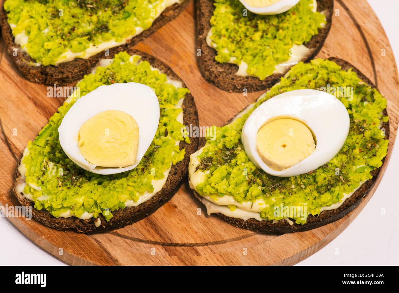 Sandwich mit Avocado und Ei auf einem Holzbrett Nahaufnahme. Essen zum Frühstück, Mittag- oder Abendessen. Gesundes Essen, vegetarische Snacks. Draufsicht, flach liegend. Stockfoto