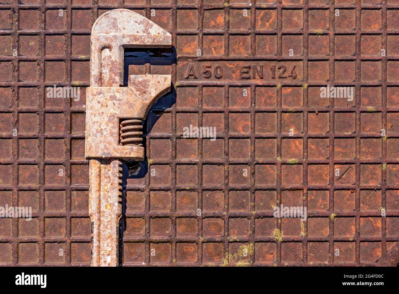 Alter verstellbarer Schraubenschlüssel, Rollgabelschlüssel oder Engländer, rostig Werkzeug auf nasser rostiger Eisenplatte, Deutschland Stockfoto