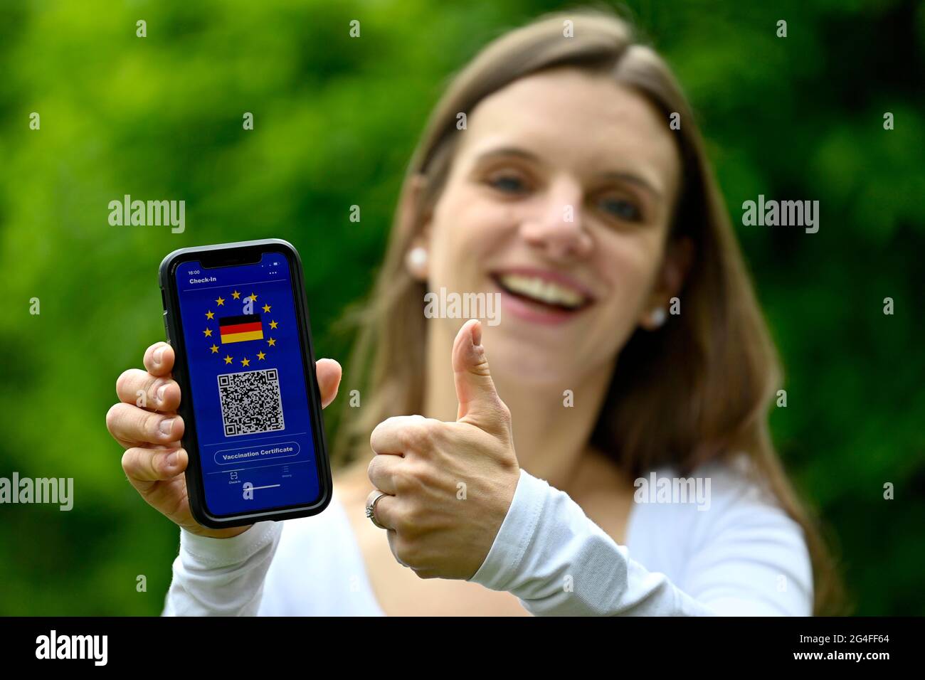 Symbol Foto-Impfung Privileg, junge Frau hält Smartphone mit digitalen europäischen Impfpass für deutsche Bürger, mit QR-Code Stockfoto