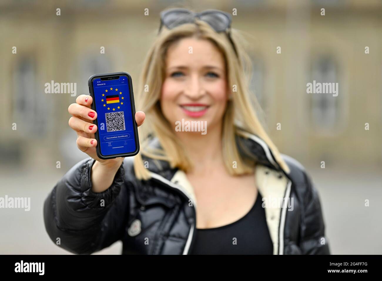 Symbol Foto-Impfung Privilegien, junge Frau hält Smartphone mit digitalen europäischen Impfpass für deutsche Bürger, mit QR-Code Stockfoto