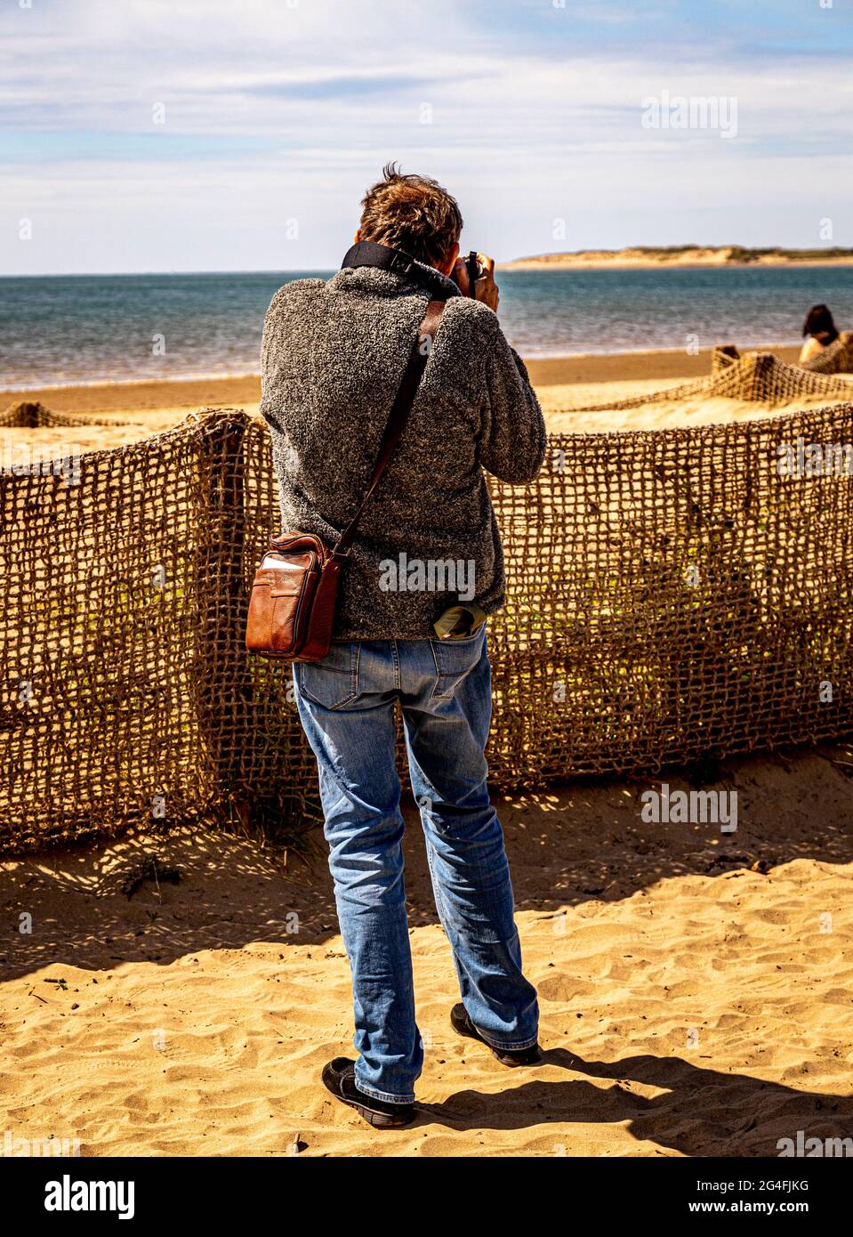 Ein begeisterter Fotograf, der am Strand fotografiert Stockfoto