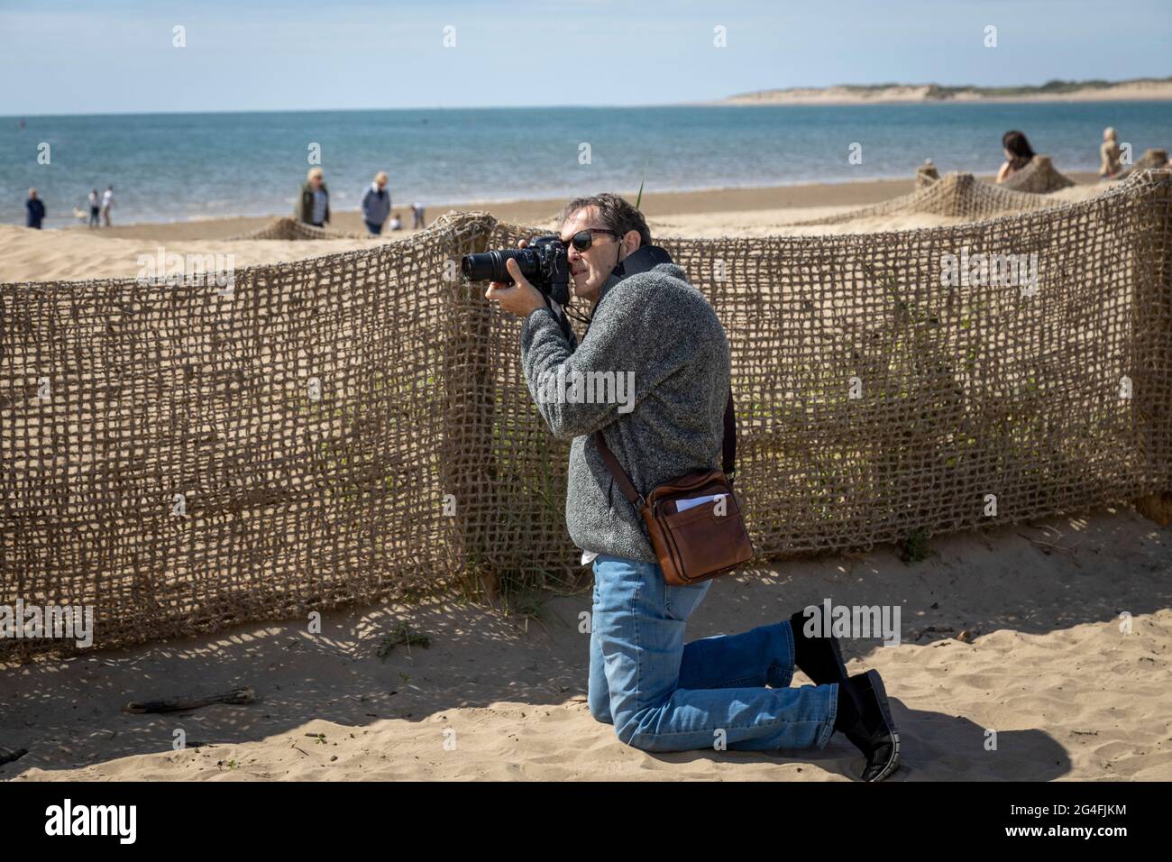 Ein begeisterter Fotograf, der am Strand fotografiert Stockfoto