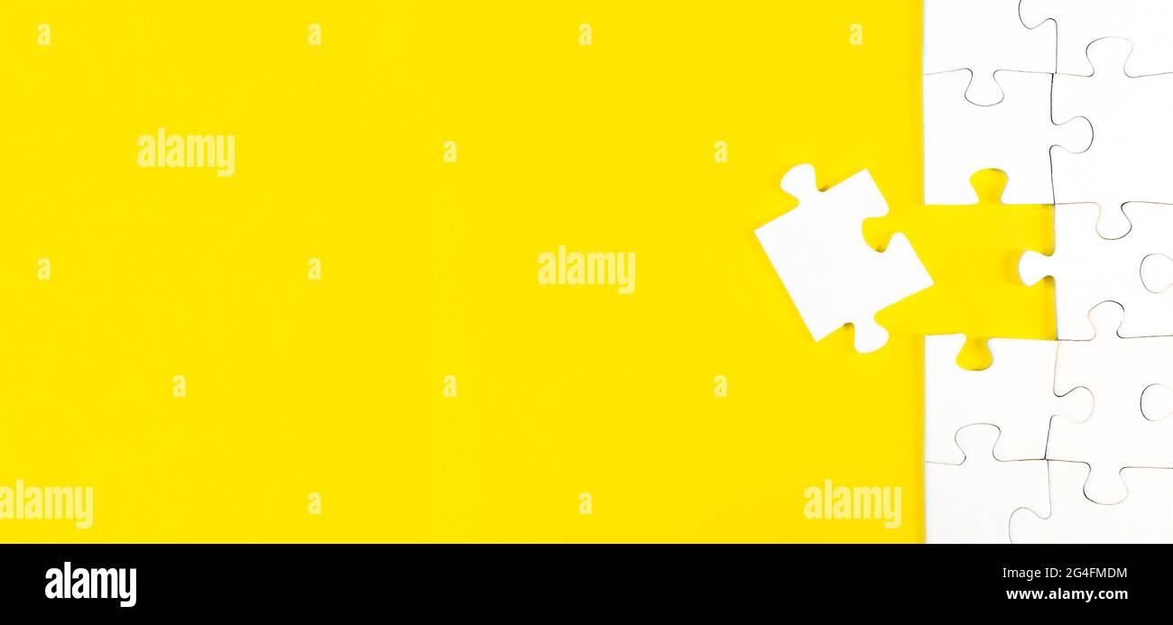 Draufsicht des Puzzles mit einem Stück links auf gelbem Hintergrund, Abschluss einer Aufgabe oder Lösung eines Problemkonzepts Stockfoto