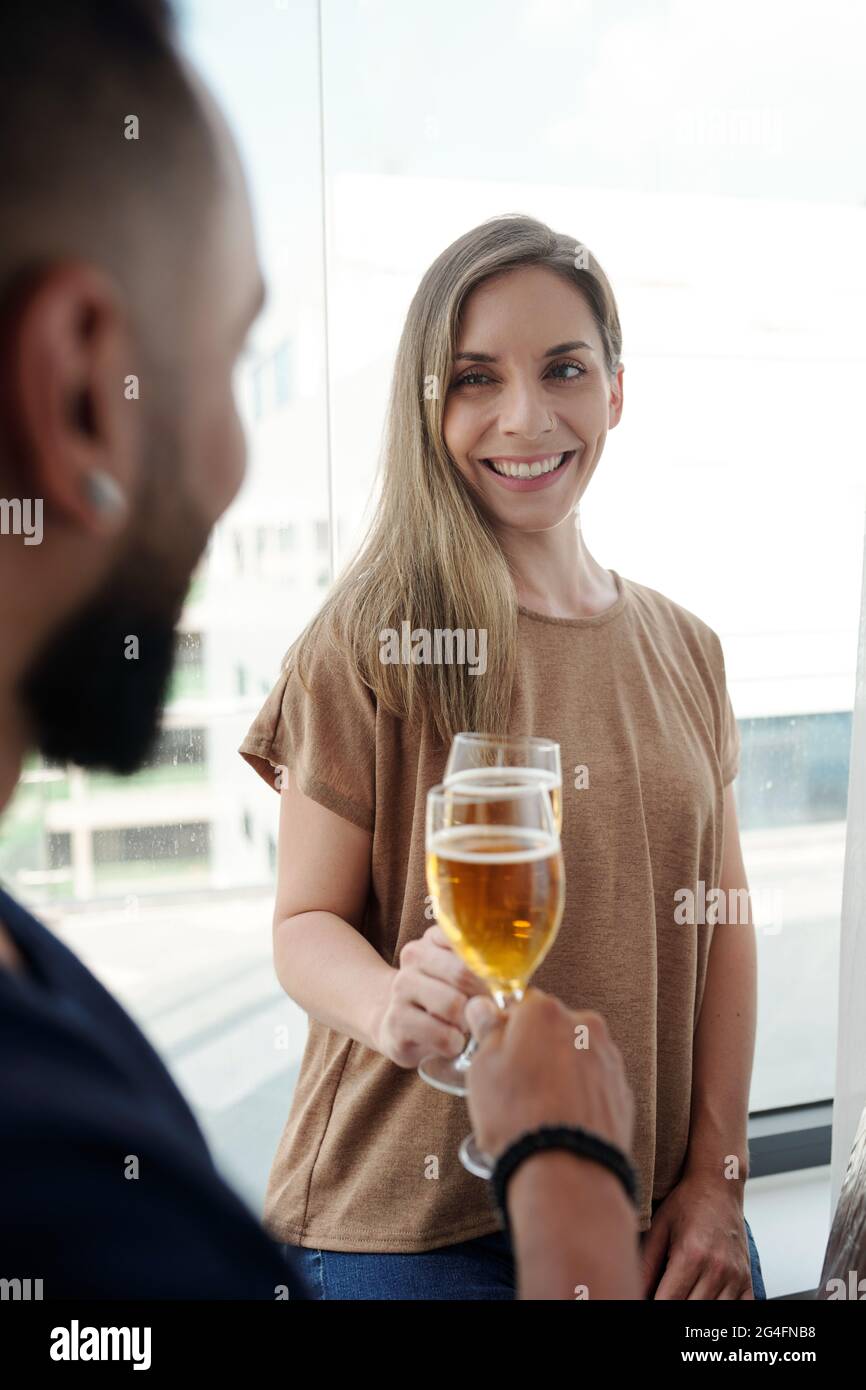 Lächelnde, hübsche Frau, die mit einem Freund auf der Hausparty Champagner trinkt Stockfoto