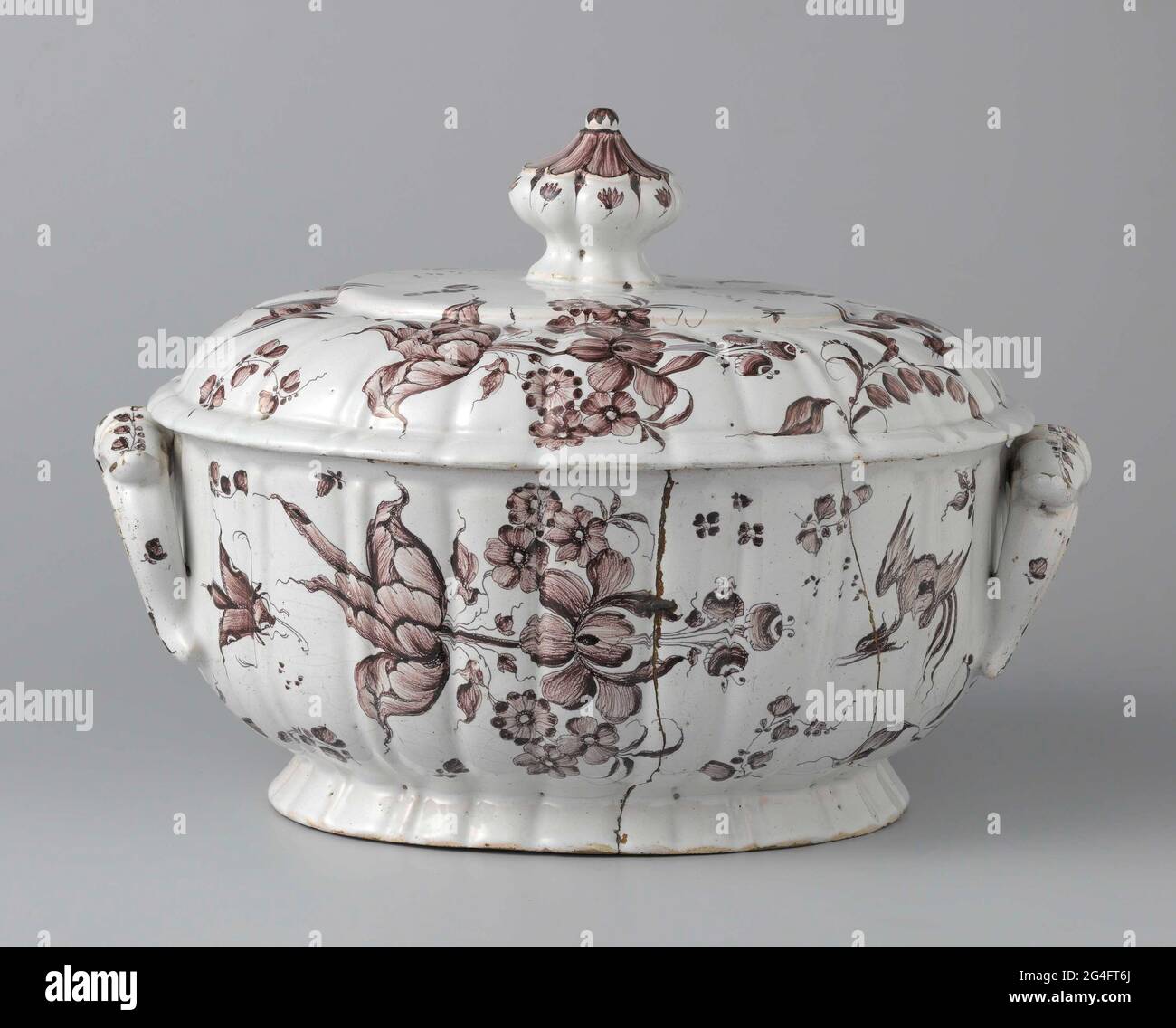 . Ovale Terrine aus Mangan bemalter Fayence. Die Terrine hat einen Fuß und einen Deckel. Die Terrine hat zwei Ohren, die an der Terrine befestigt sind, und der Deckel hat einen Knopf. Die Terrine und der Deckel sind in Mangan mit zwei Blütenzweigen, zwei fliegenden Vögeln und Stipelpaketen bemalt. Stockfoto
