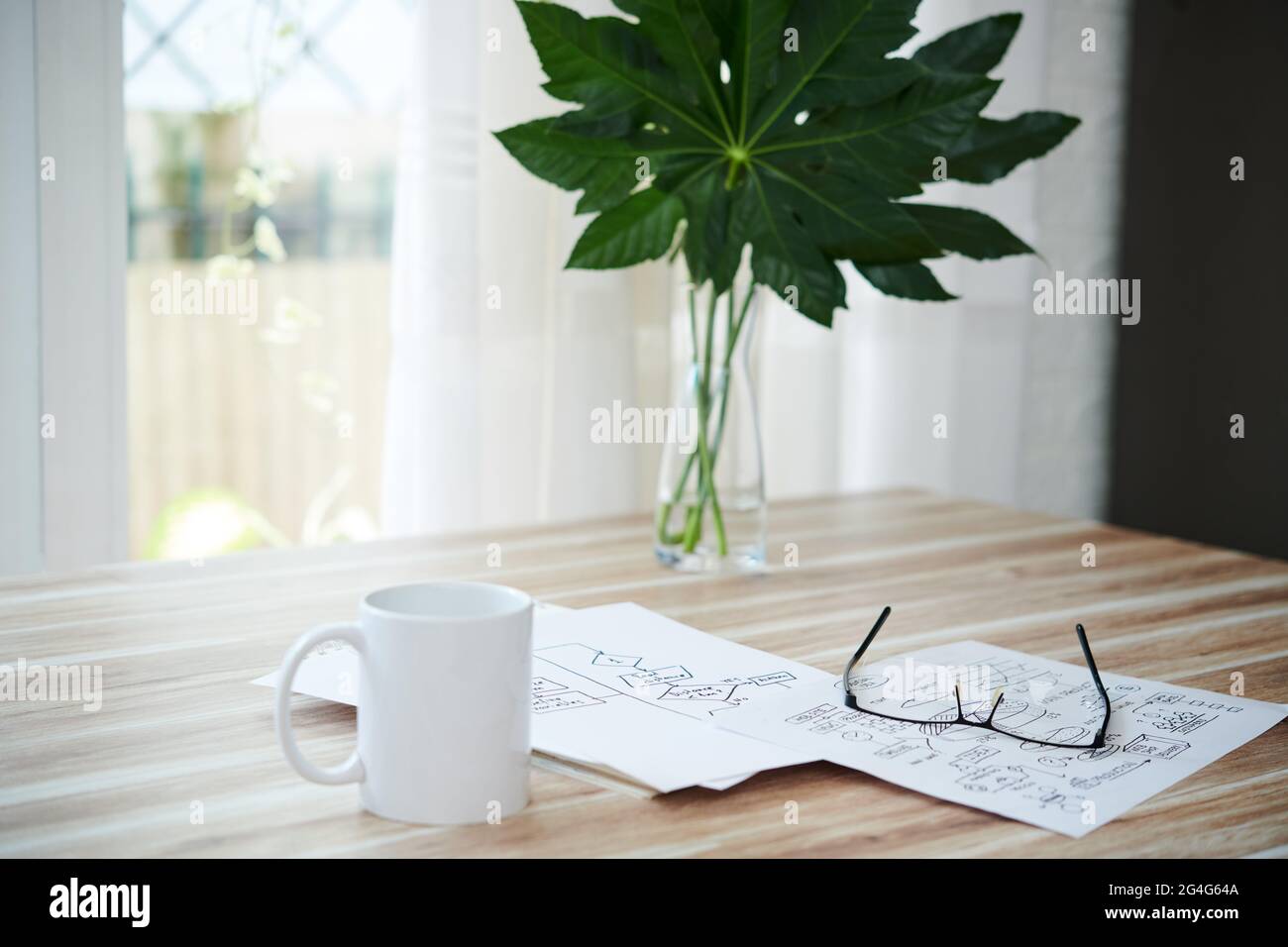 Tasse Kaffee, Gläser und Dokumente mit Blockschemata auf dem Tisch zu Hause Stockfoto