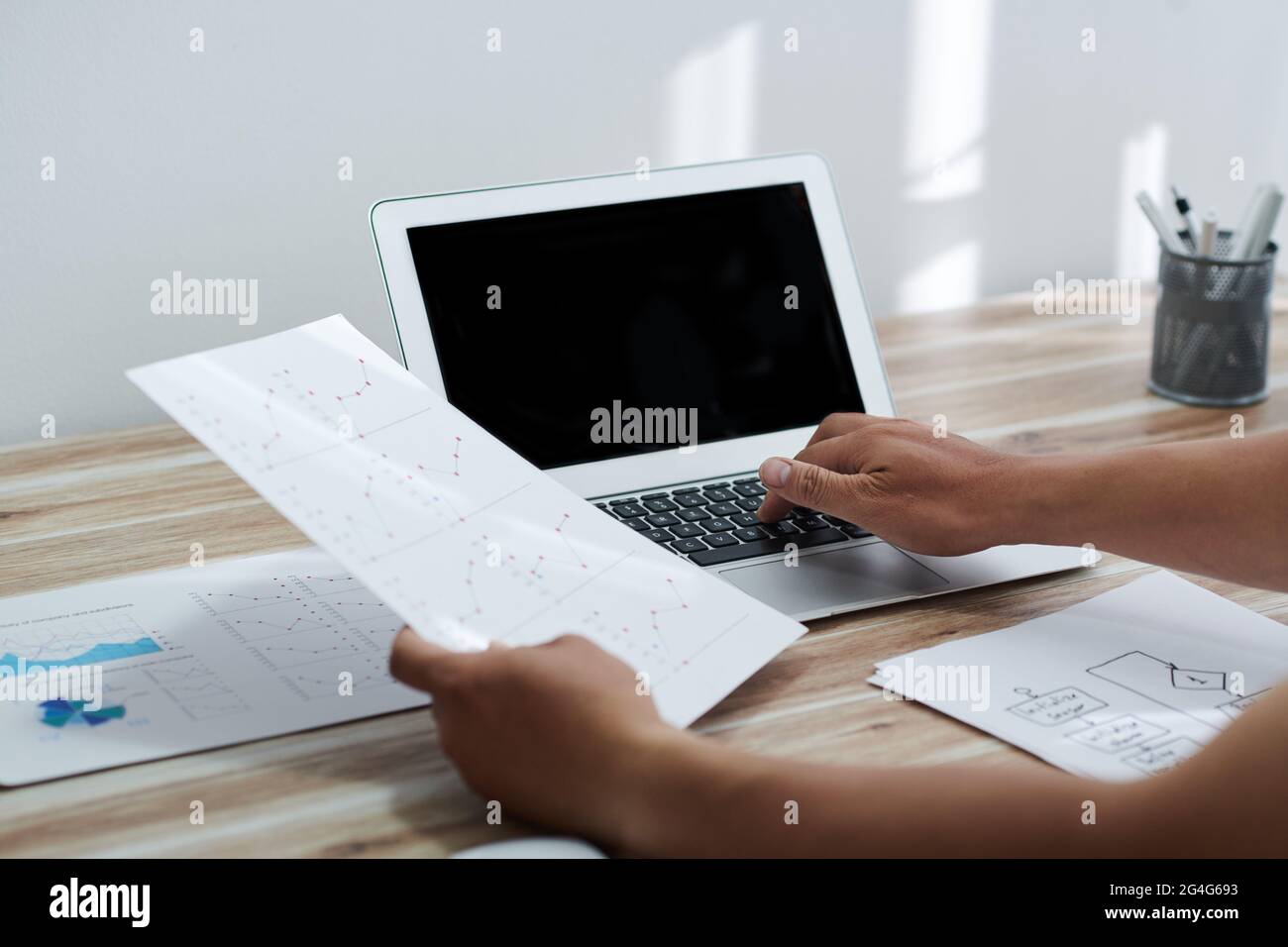 Hände des Unternehmers, die Liniendiagramme bei der Arbeit am Laptop am Schreibtisch im Heimbüro überprüfen Stockfoto