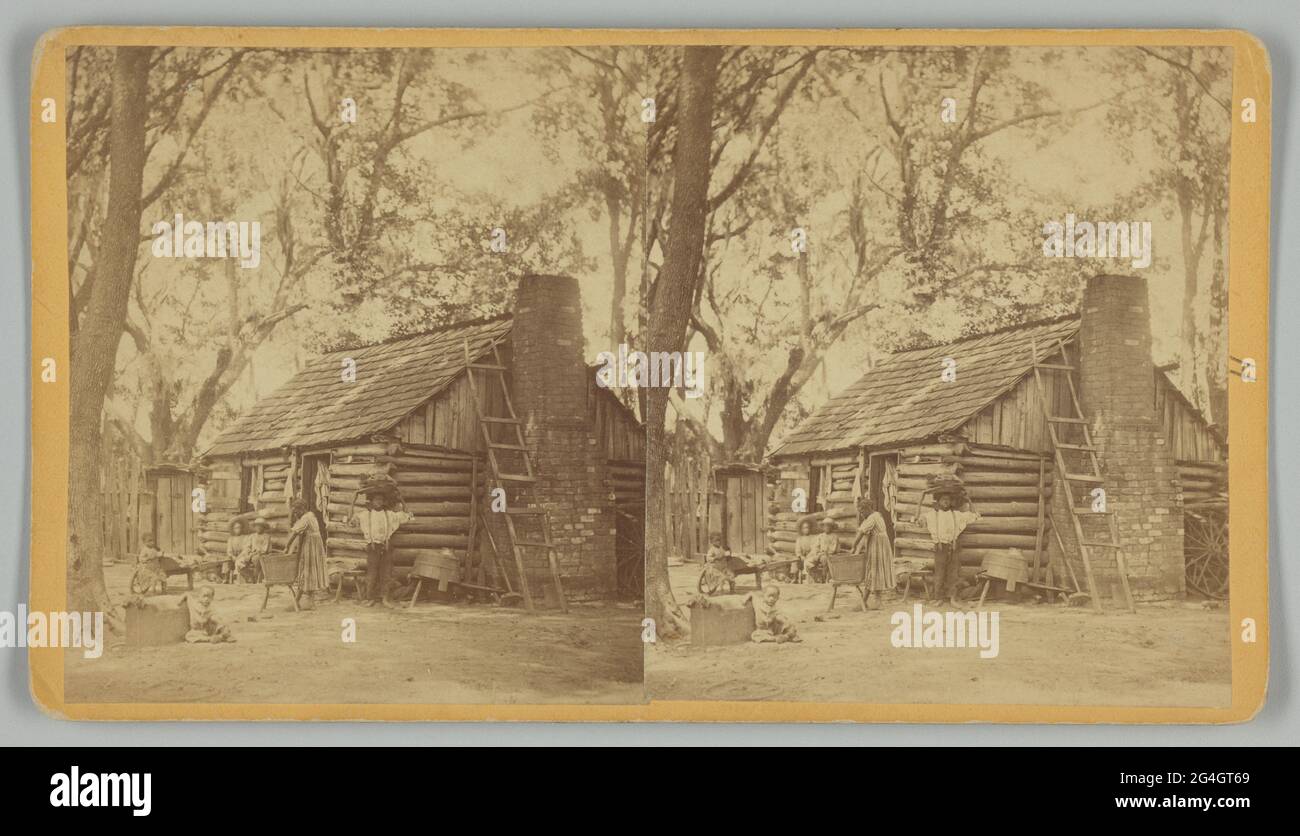 Ein Stereograph mit dem Titel „Plantation Scene; Folks All Home“, gedruckt von J. N. Wilson aus Savannah, Georgia. Die Albuminabzüge zeigen sechs (6) nicht identifizierte afroamerikanische Kinder im Hof vor einem Blockhaus mit einem Ziegelkamin. Ein Mädchen steht in der Nähe der Mitte mit ihren Händen in einem hölzernen Waschbecken auf einem Ständer. Ein Junge steht zu ihrer rechten Seite mit seinem Rücken an der Ecke des Gebäudes und hält einen großen vollen Korb auf seinem Kopf. Zwei jüngere Kinder sitzen auf einer Bank außerhalb des Gebäudes im Hintergrund. Zwei Kleinkinder sitzen auf der linken Seite des Rahmens, eines auf dem Rad eines kleinen Holzes Stockfoto