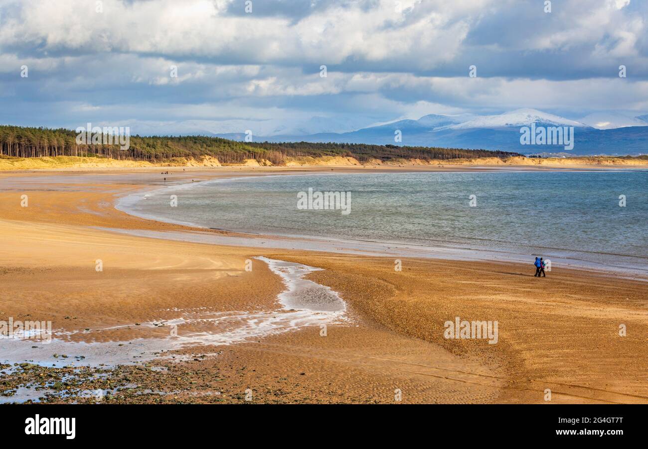Newborough Beach bei Ebbe von Llanddwyn Island mit den schneebedeckten Bergen von Snowdonia im Hintergrund, Isle of Anglesey, Nordwales Stockfoto
