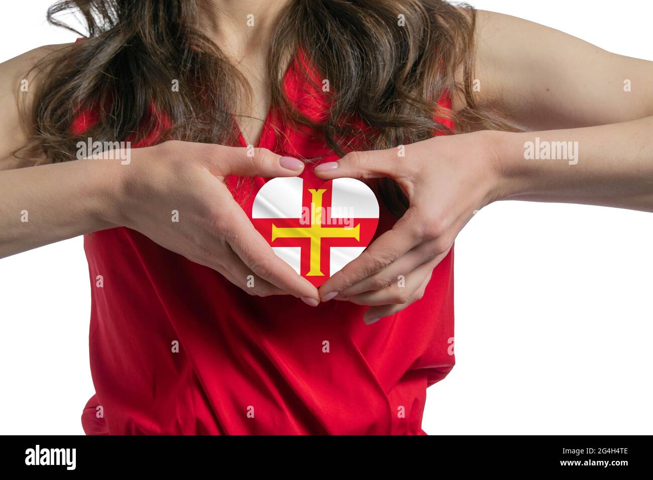 Ich Liebe Guernsey. Die Frau hält ein Herz in Form der Flagge von Guernsey auf ihrer Brust. Konzept des Patriotismus. Stockfoto