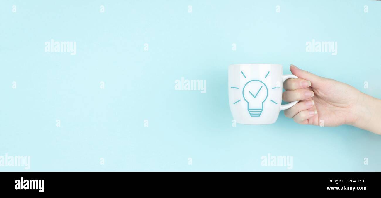 Kreative Idee.Konzept der Idee und Innovation. Mädchen Hand halten Morgen Kaffeetasse mit Schild Licht Bulp Symbol auf blauem Hintergrund. Lösungsanalyse und de Stockfoto