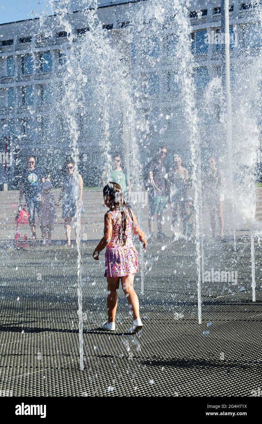 Menschen am Brunnen, abnorme Hitze in Russland. Ein kleines Mädchen läuft unter den kalten Wasserstrahlen. Uljanowsk, Russland, 19. Juni 2021 Stockfoto