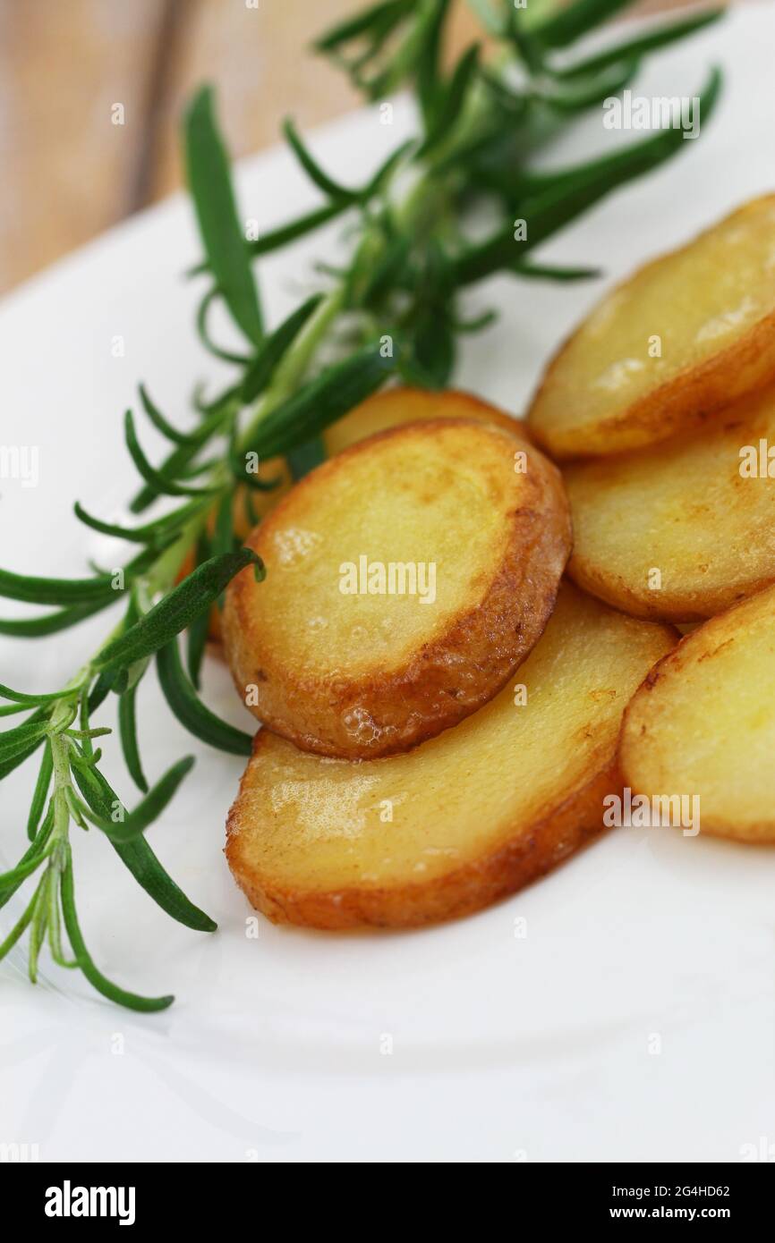 Scheiben knusprig gebratene Kartoffeln mit Schale mit frischem Rosmarin, Nahaufnahme Stockfoto