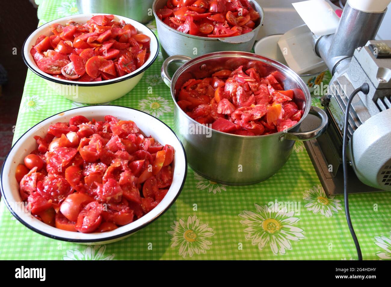 Herstellung von Tomatensaft zu Hause. In Scheiben geschnittene Tomaten in Töpfen. E Drücken Sie die Taste für die Tomate. Stockfoto