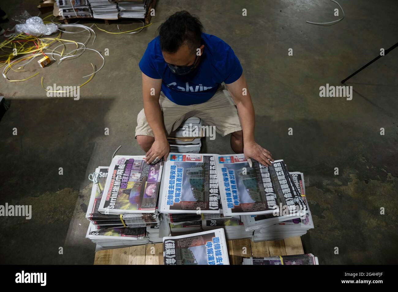 Hongkong, China. Juni 2021. In der Druckerei der Zeitungsbüros der Apple Daily in Hongkong stellt ein Mitarbeiter Abschnitte mit frisch gedruckten Papieren zusammen.die prodemokratische Zeitung Apple Daily in Hongkong hat angekündigt, dass sie ihren Betrieb bis Ende der Woche einstellen wird, nachdem die Behörden ein durchschlagenes nationales Sicherheitsgesetz zum Einfrieren verwendet haben Die Vermögenswerte des Unternehmens und verhaften führende Redakteure und Führungskräfte. Kredit: SOPA Images Limited/Alamy Live Nachrichten Stockfoto