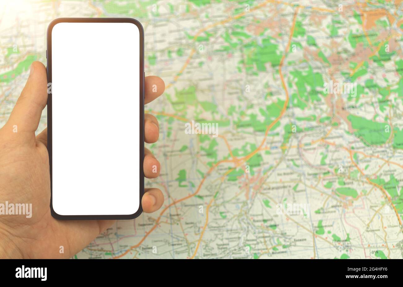 Mann hält und benutzt Mobiltelefon mit leerem weißen Bildschirm auf einem Hintergrund von Stadtplan, Kartennaigationskonzept, Kopierraum, Mockup Stockfoto