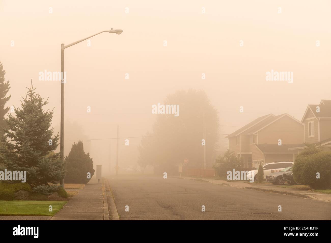 Wohnstraße mit Dunst und rauchigem Himmel von Waldbränden Stockfoto