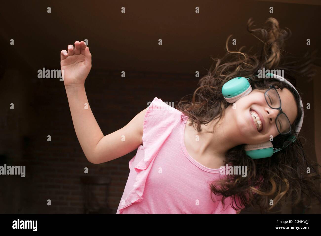 Mädchen mit Kopfhörer grüne Brille und lächelnd hört Musik tanzen, die in der Stimmung ist Stockfoto