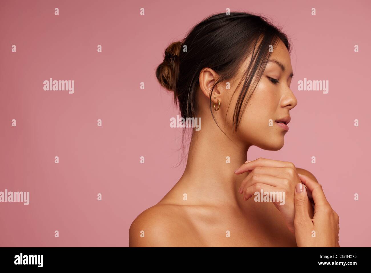 Junge asiatische Frau mit schöner Haut. Schönes Weibchen mit geschlossenen Augen vor rosa Hintergrund. Stockfoto
