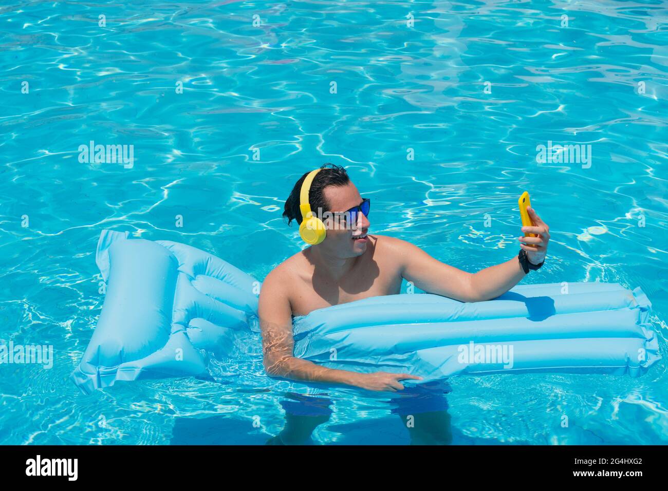 Mann, der sich am Pool sonnt und das Handy in der Hand hält Stockfoto