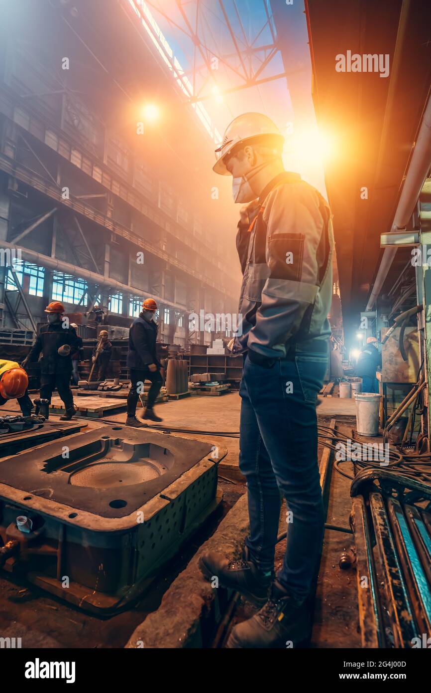 Arbeiter in Uniformen, Helmen und Schutzmasken im metallurgischen Werk. Stahlproduktion. Stockfoto