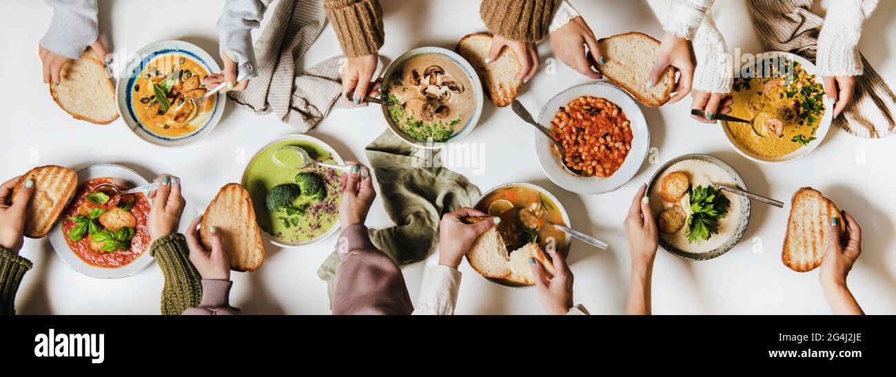 Menschen essen gemeinsam verschiedene cremige vegane Herbst- und Wintersuppen Stockfoto
