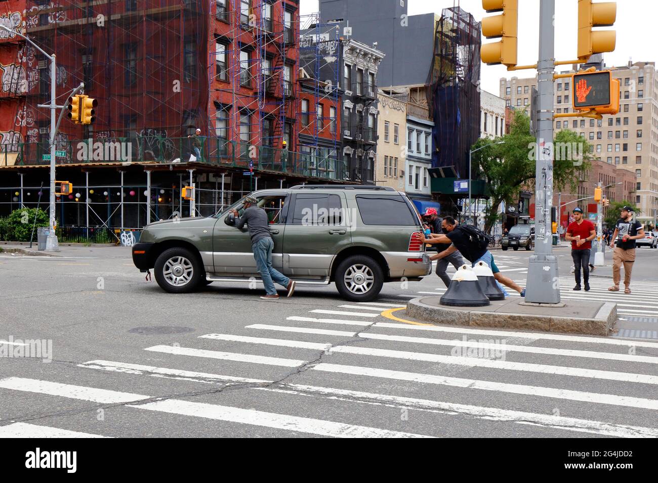 Menschen, die ein behinderten Auto über eine Kreuzung in New York City schieben. Stockfoto