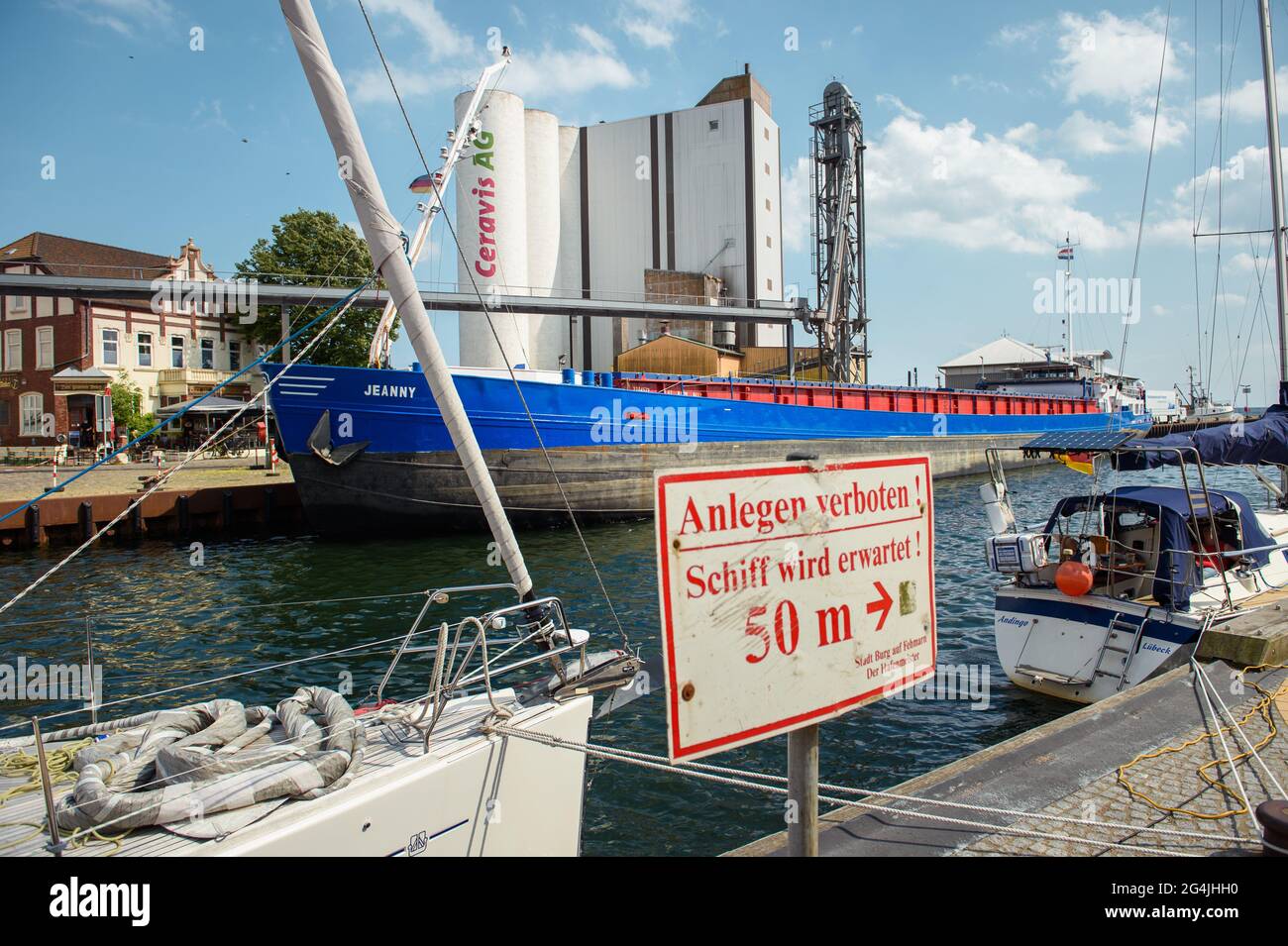 Fehmarn, Deutschland. Juni 2021. Das Mehrzweckschiff "Jeanny" wird im Stadthafen Burgstaaken vor Silos für Futter und Dünger vertäut. Das Hafen Becken ist, zu einer Tiefe von fünf Metern auszubaggern, um das kleine Hafen konkurrenzfähig wieder zu machen. (To dpa 'Fehmarn will den Stadthafen Burgstaaken vertiefen') Quelle: Gregor Fischer/dpa/Alamy Live News Stockfoto