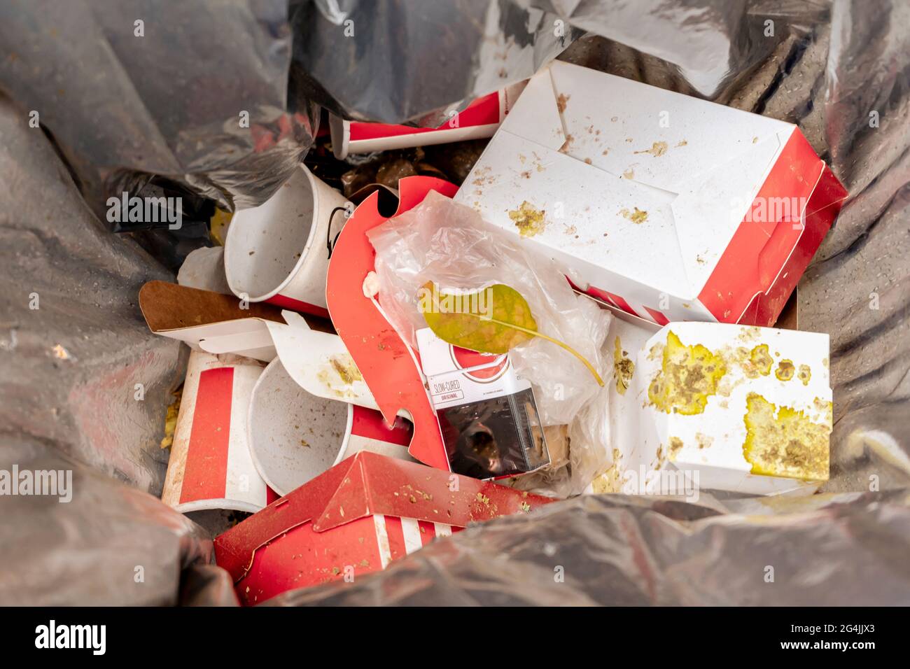 Mülltonne mit den Resten von Einweg-Lebensmittelverpackungen und Einweg-Gläser von alkoholfreien Getränken. Konzept für Ökologie und Umweltschutz Stockfoto