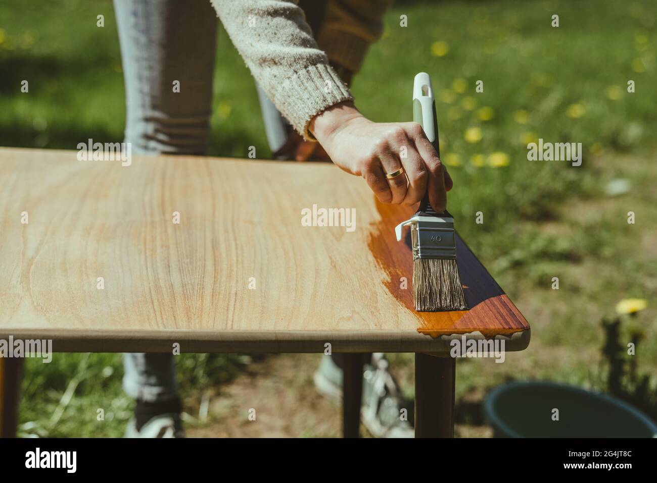 Selektiver Fokus einer Malerhand, die Polyurethan auf einen Holztisch applyte Stockfoto