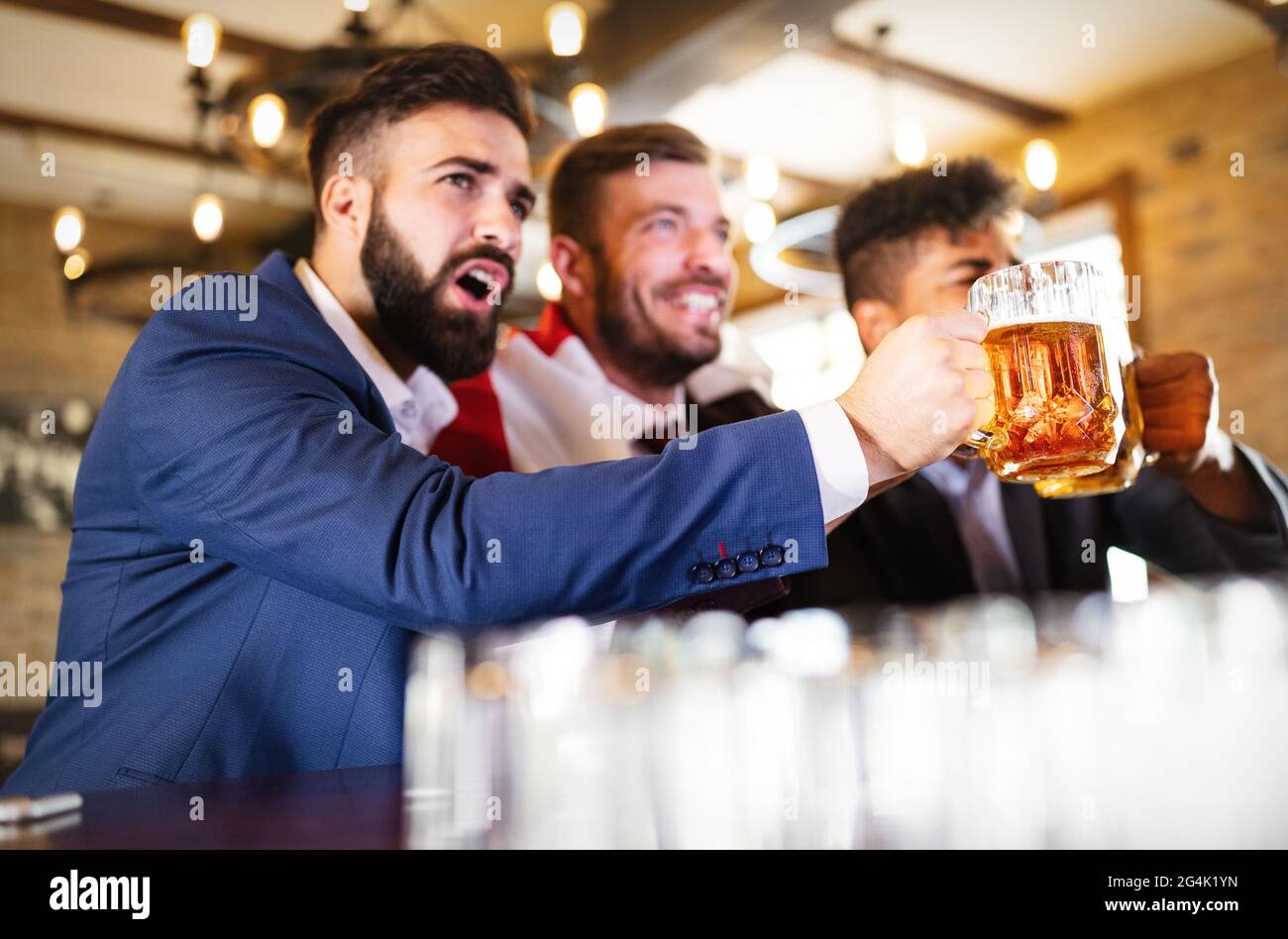Männerfans schreien und beobachten Fußball im Fernsehen und trinken Bier in einer Kneipe Stockfoto