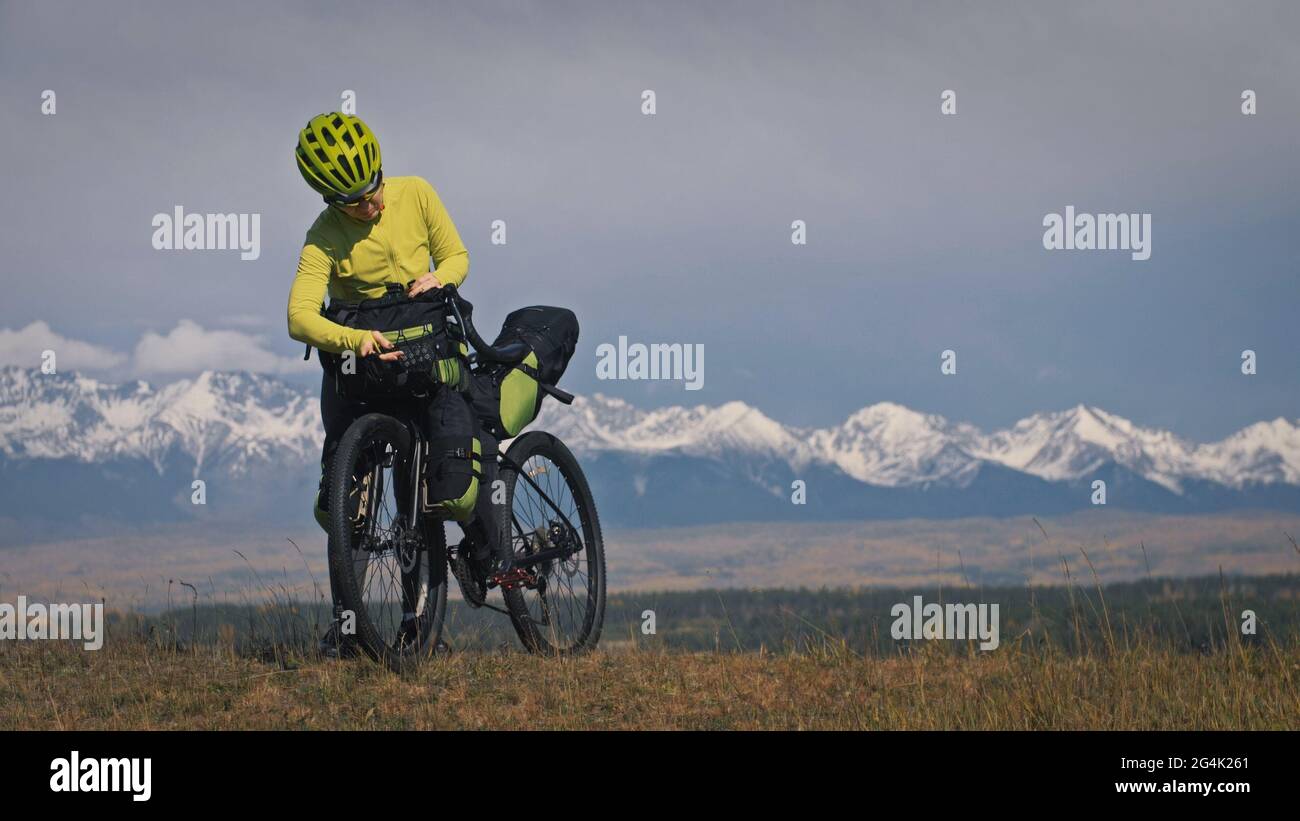 Die Frau reist auf gemischtem Terrain mit Bikepacking. Die Reise des Reisenden mit Fahrradtaschen. Sport Tourismus Bikepacking. Stockfoto