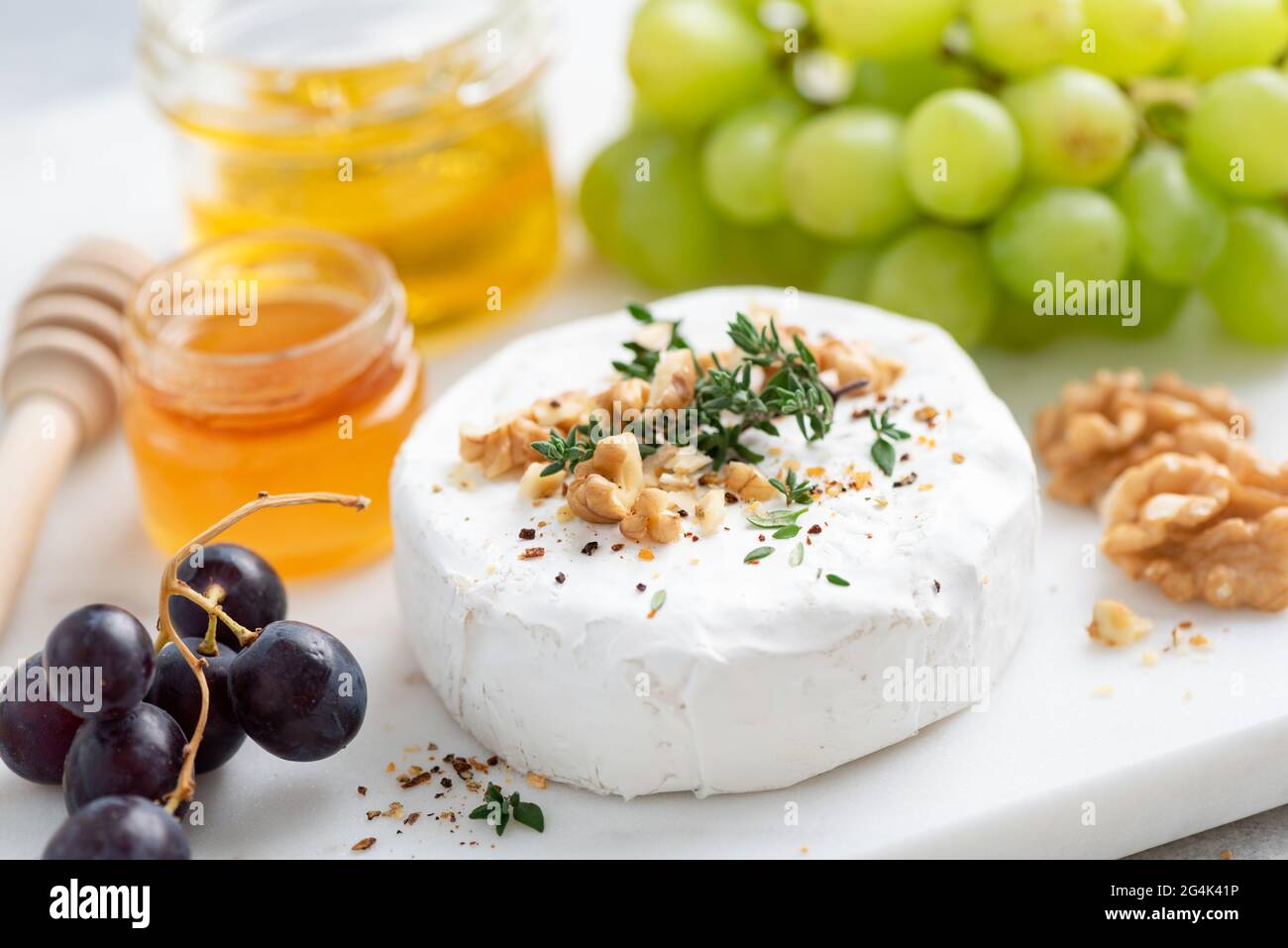 Camembert Käse serviert mit Walnüssen, Trauben und Honig. Nahaufnahme. Gourmet-Weißkäse Stockfoto
