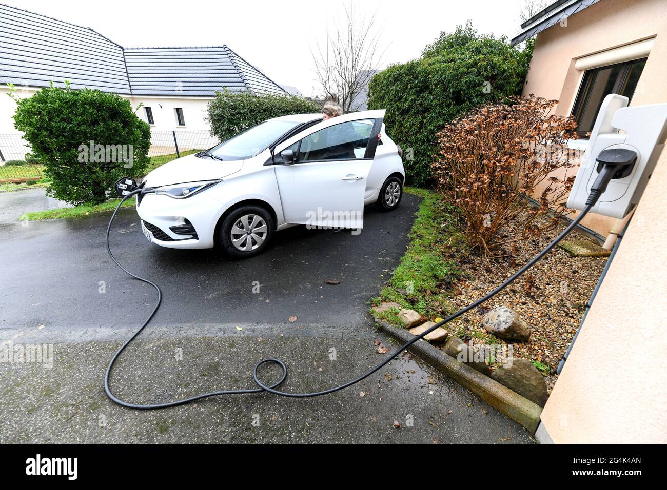 Renault Zoe Elektroauto. Frau lädt die Batterie ihres Fahrzeugs zu Hause auf Stockfoto