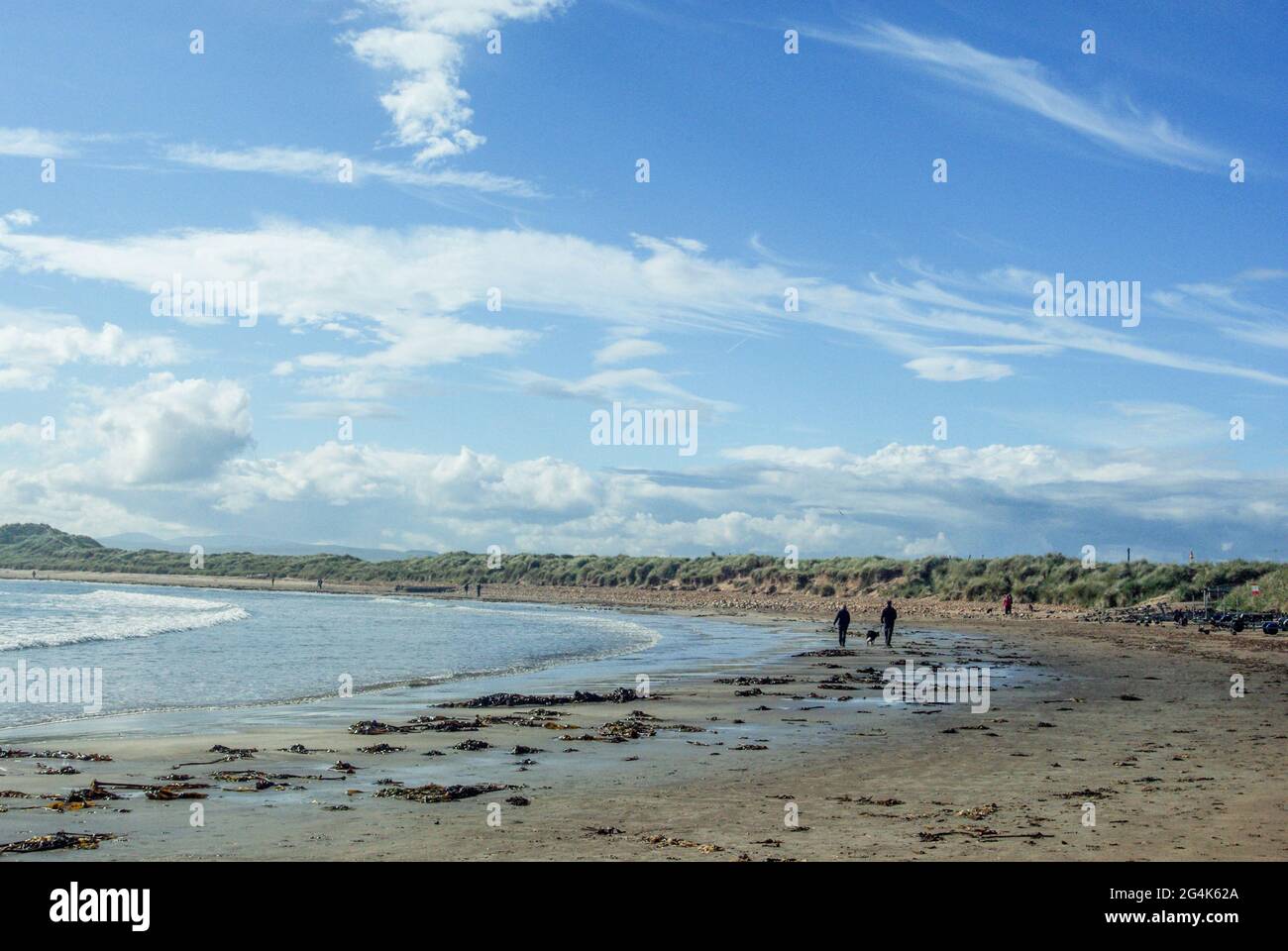 Beadnell Harbour, Beadnell, Northumberland, Großbritannien; Besucher, die im Sommer am Strand spazieren Stockfoto