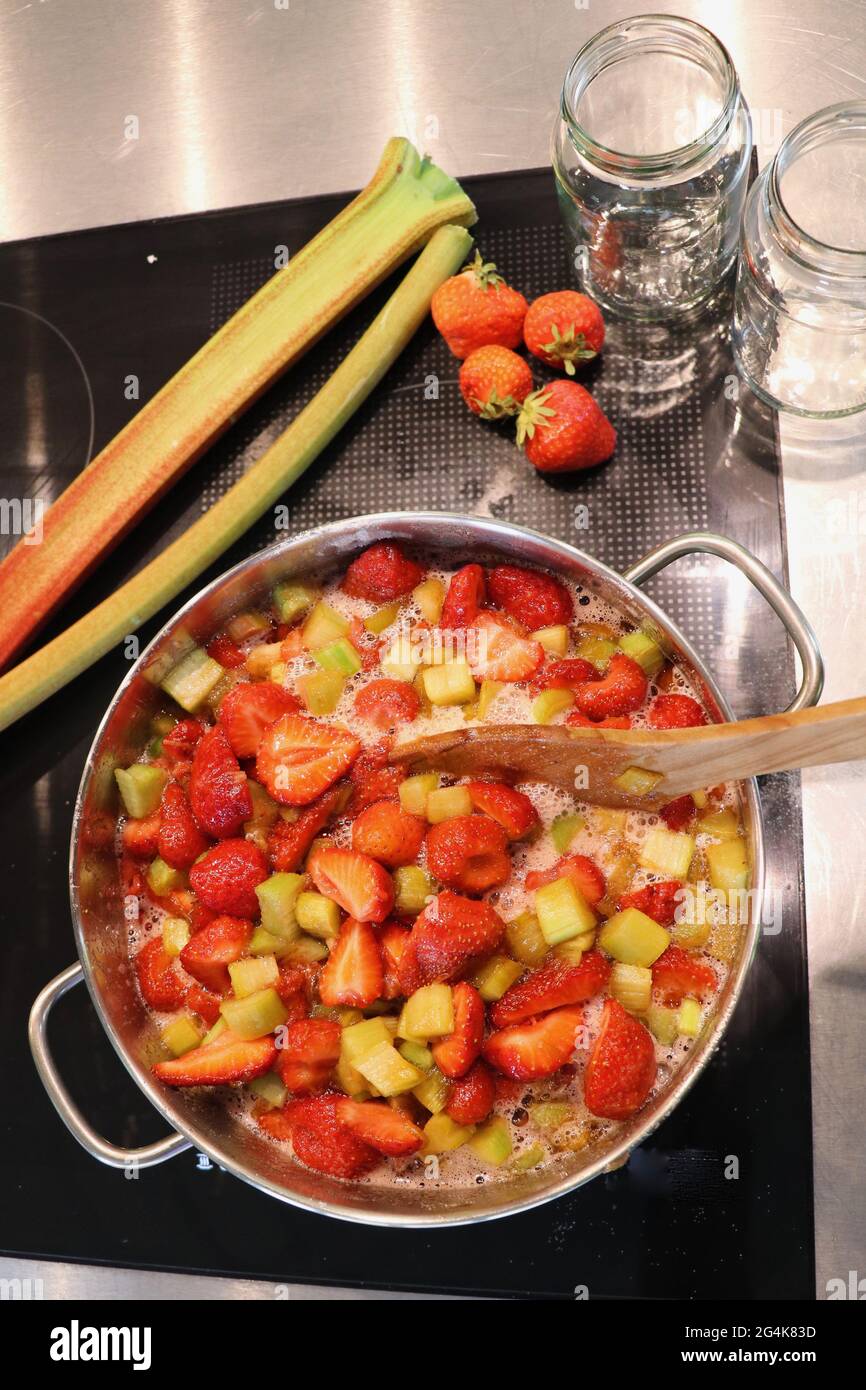 Blick von oben auf den Kochtopf mit Rhabarber und Erdbeeren für hausgemachte Marmelade Stockfoto