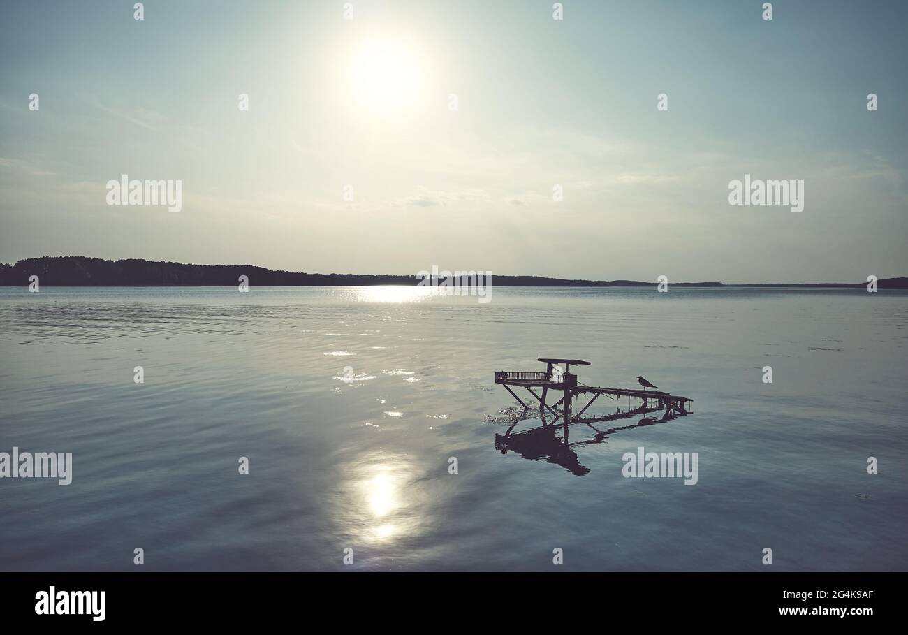 Alte hölzerne Angelplattform bleibt im See gegen die Sonne, Farbtonierung angewendet. Stockfoto