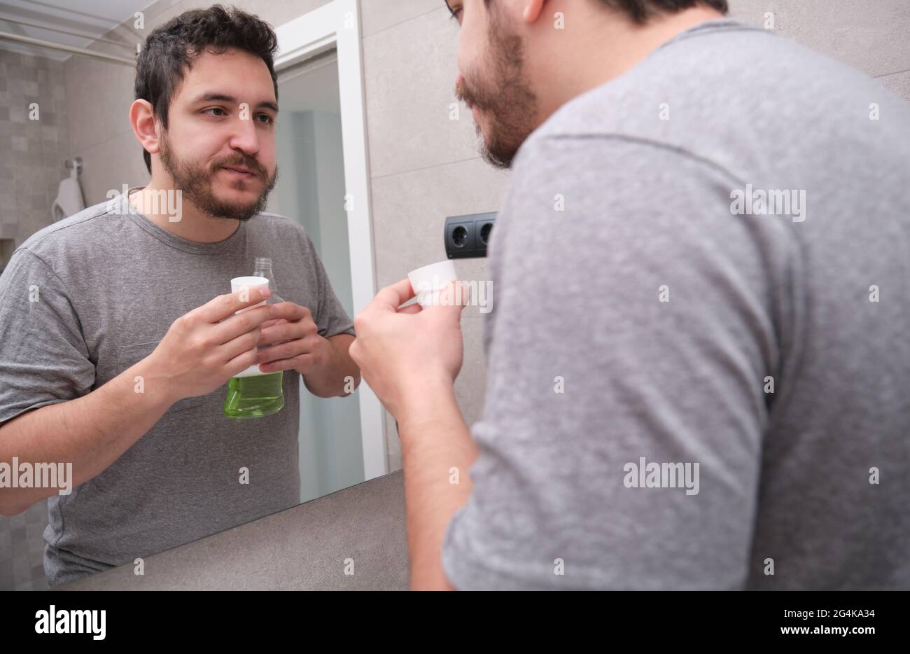 Müde, müde Mann, der im Badezimmer den Mund mit grünem Mundwasser spült. Zahnpflegekonzept. Stockfoto