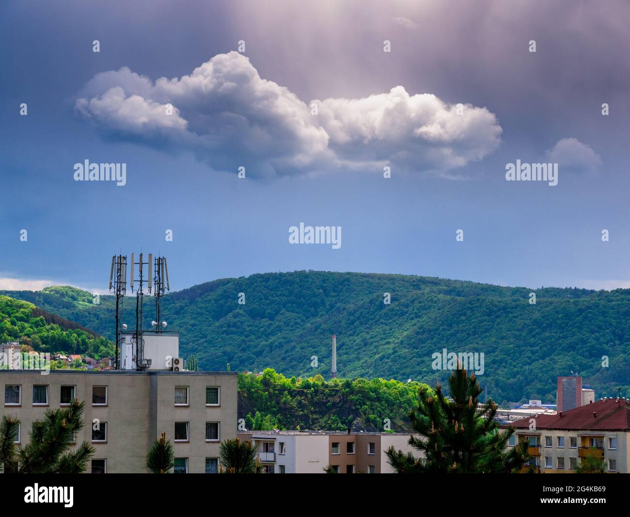 5G-Telekommunikationssender auf dem Dach eines Mehrfamilienhauses mit Wolken und Sonnenlicht am dunklen Himmel Stockfoto
