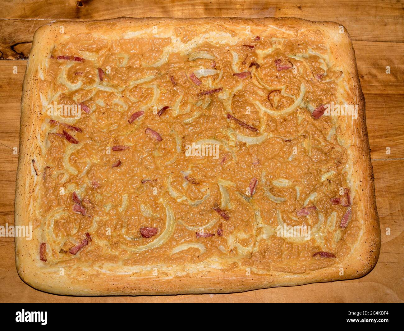 Pikanter Kuchen mit Zwiebeln und Wurst, bedeckt mit geschlagenem gebackenem Ei Stockfoto