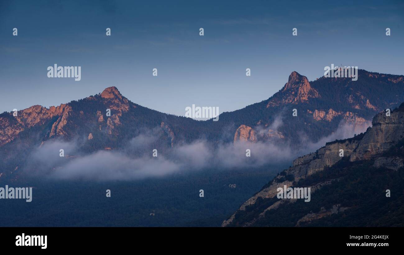 Sonnenaufgang durch Nebel auf den Gipfeln CIM d'Estela und Roc d'Auró, im Rasos de Peguera (Berguedà, Katalonien, Spanien, Pyrenäen) Stockfoto