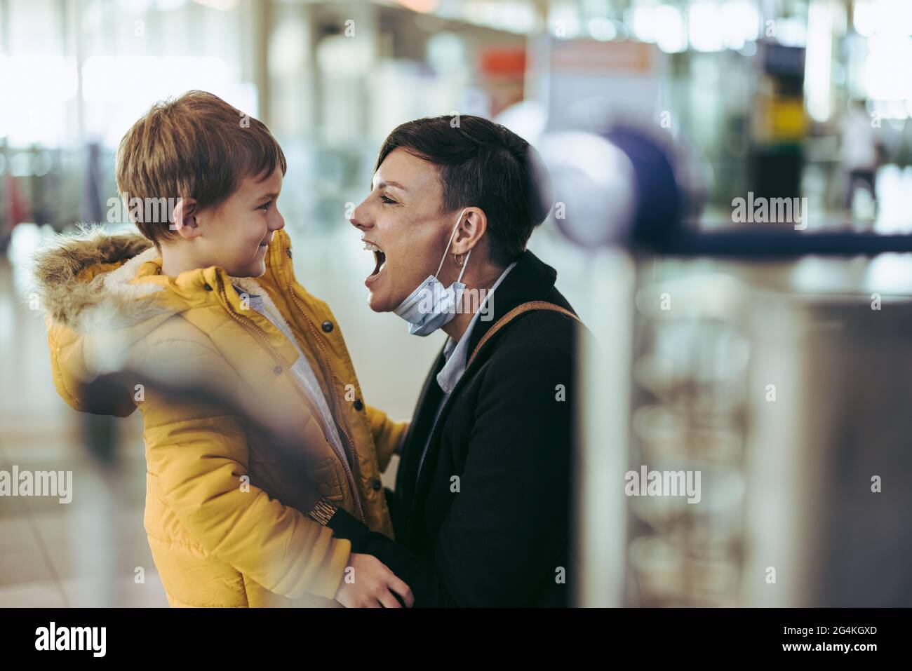 Aufgeregte Frau, die ihren Sohn am Flughafen trifft. Mutter trifft ihren Sohn nach langer Trennung während des Covid-19-Ausbruchs. Stockfoto