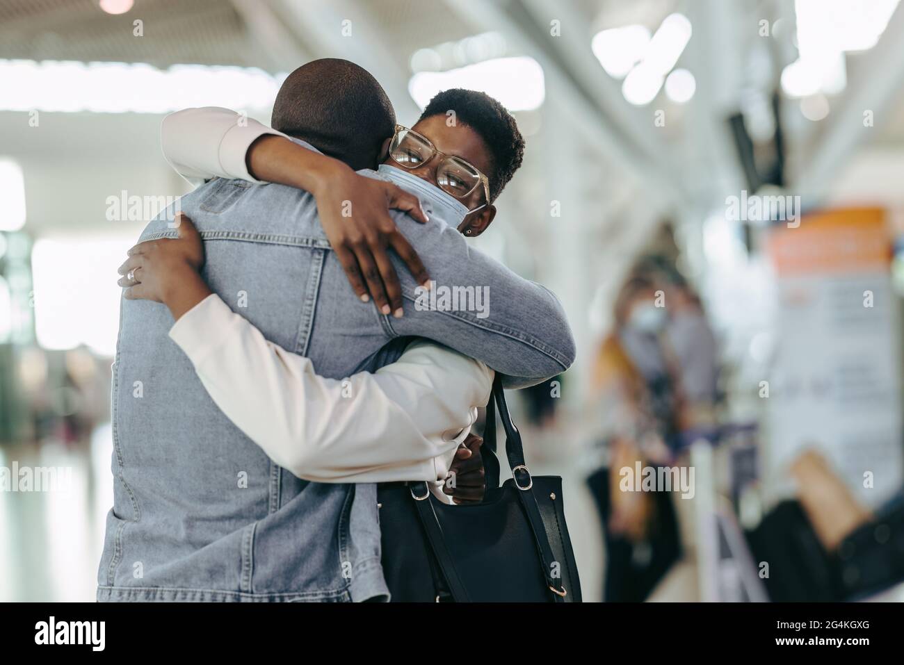 Afrikanisches Reisepaar umarmt sich am Flughafen. Mann am Flughafenterminal umarmte Frau, bevor er während einer Pandemie Auf Wiedersehen ansagte. Stockfoto