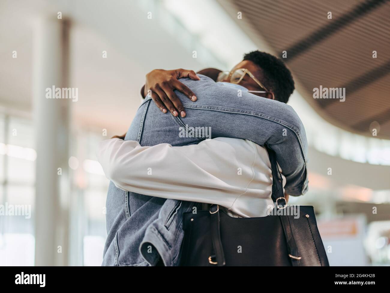 Das Passagierpaar umarmt sich am Flughafen. Ein Mann umarmte die Frau am Flughafenterminal herzlich. Stockfoto