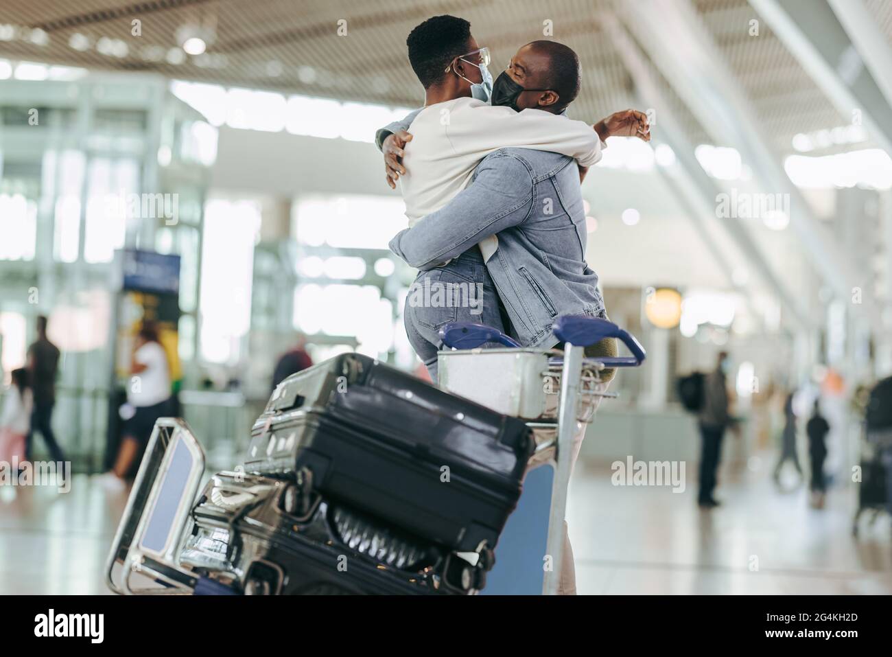 Afrikanisches Paar umarmt sich am Flughafenterminal. Mann und Frau treffen sich bei der Ankunft am Flughafen nach der Sperrung der Pandemie. Stockfoto