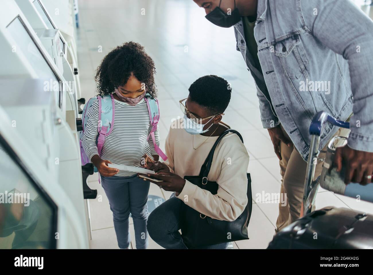 Touristenfamilie von drei Personen mit Bordkarte am Flughafenterminal. Mädchen und Mutter, die mit dem Vater am Flughafen das Flugticket angeschaut haben. Stockfoto