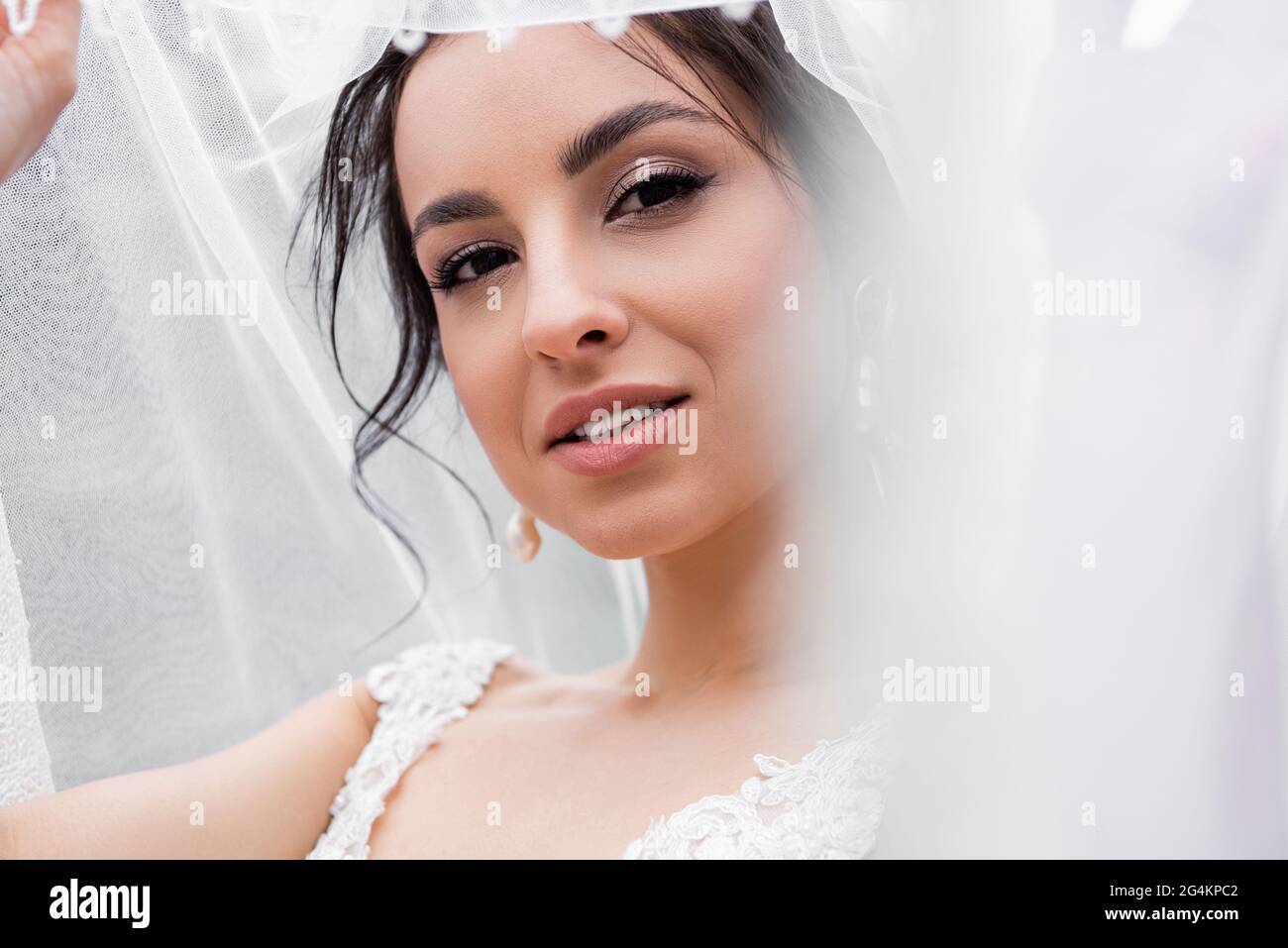 Junge Braut im Hochzeitskleid mit verschwommenem Schleier Stockfoto