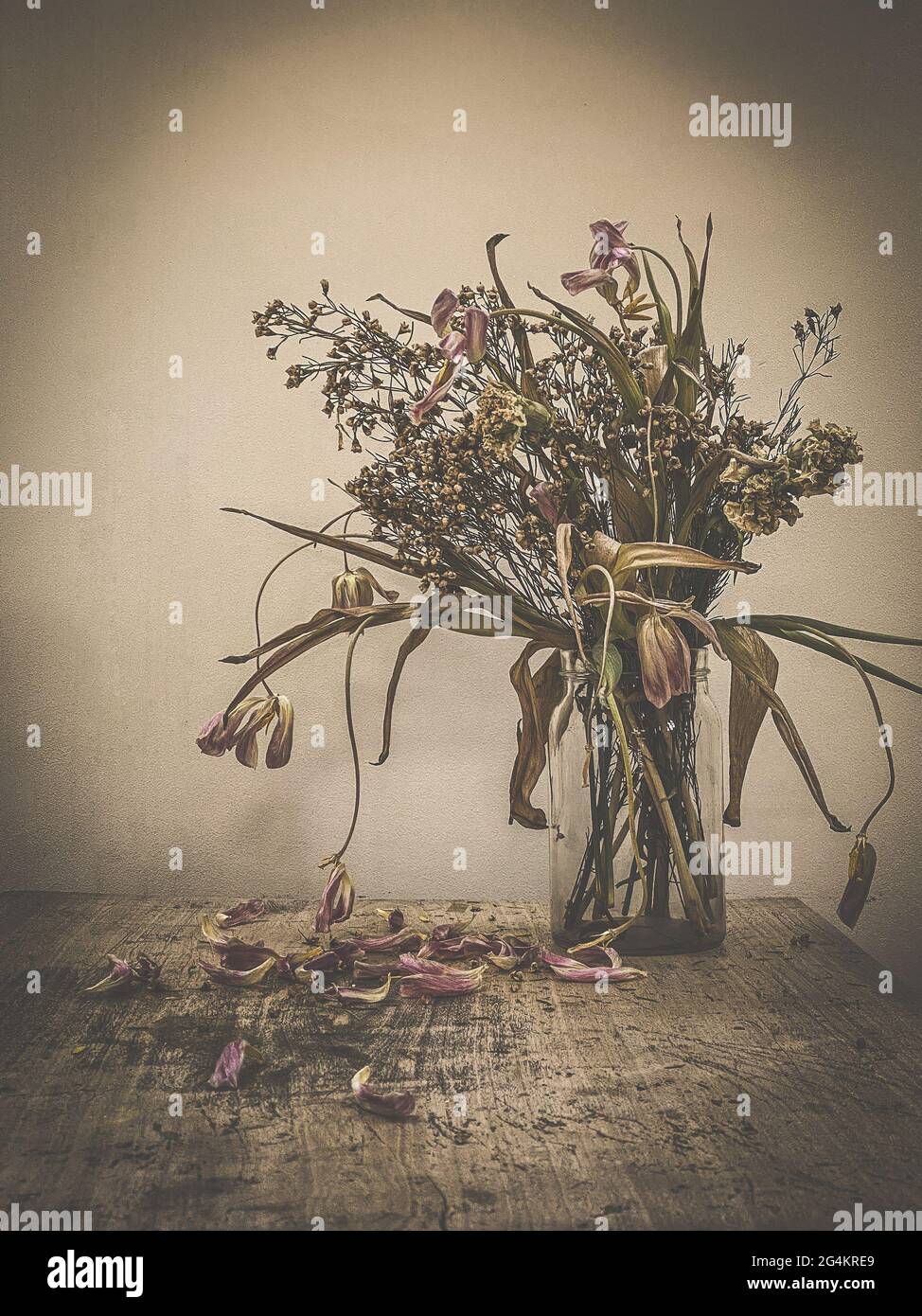 Verwelkt Blumen Bouquet in einer klaren Glasvase, Vintage gefiltert Stockfoto