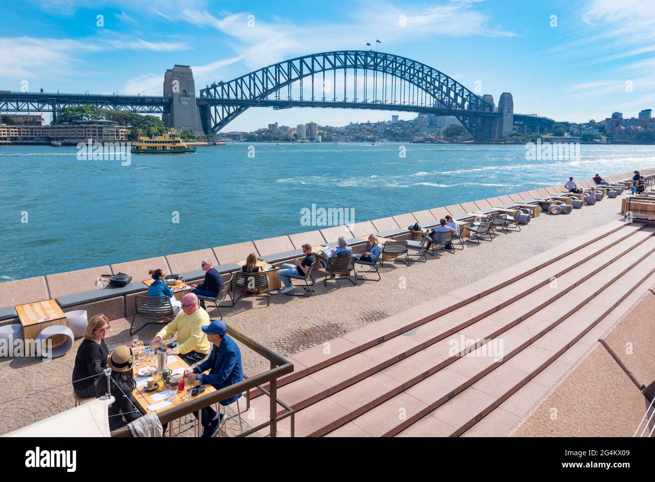 In der Mittagssonne im April in New South Wales, Australien, können Gäste neben dem Hafen von Sydney und dem Opernhaus von Sydney ihren Kaffee genießen Stockfoto